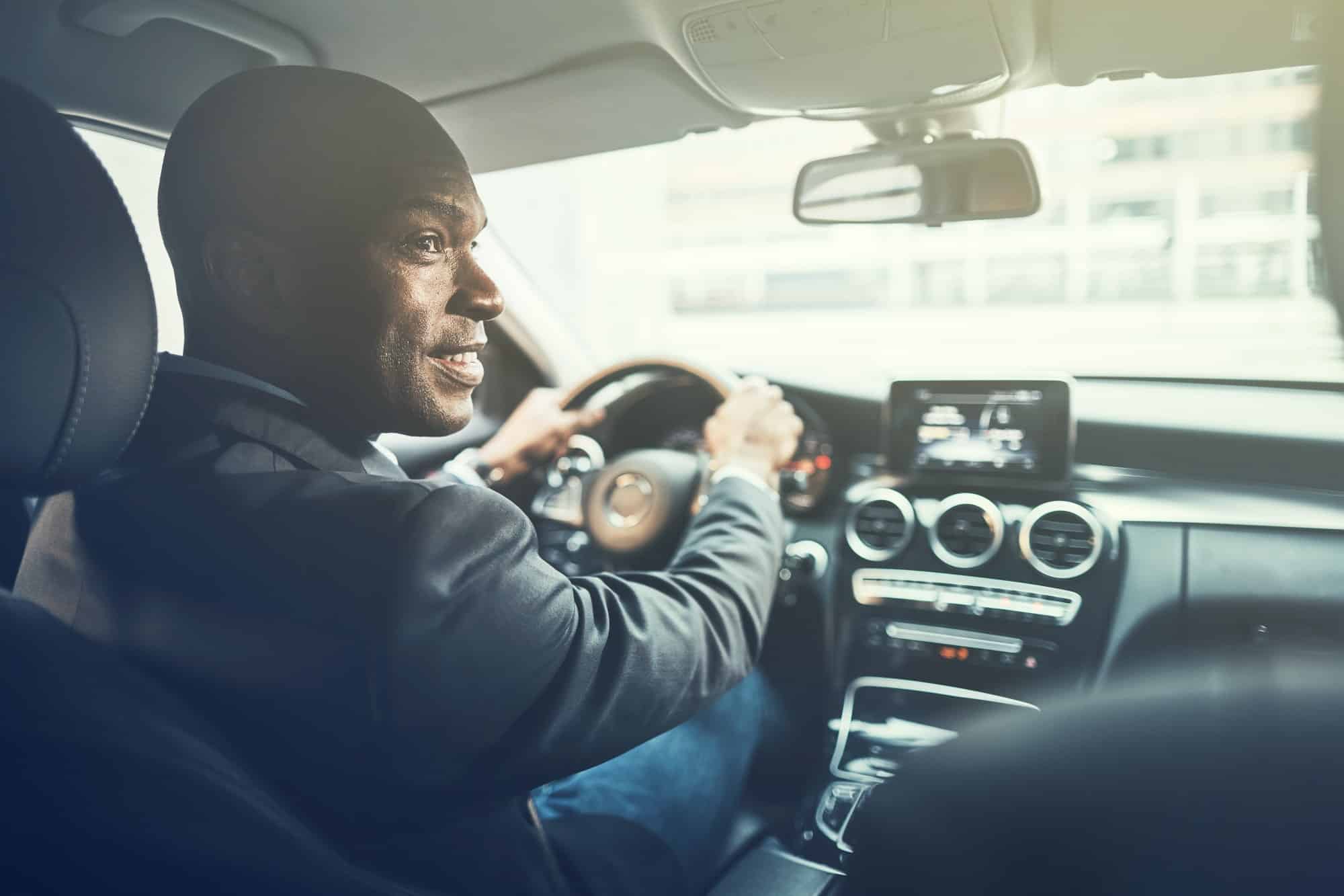 Smiling young African man driving through the city