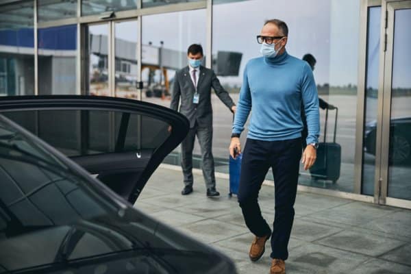 Male entrepreneur followed by the airport employee with his baggage