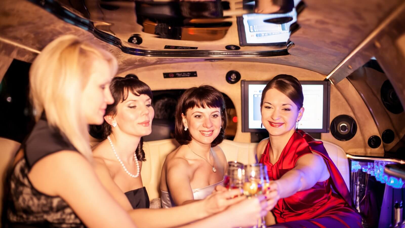 Group of friends celebrating something in luxury limousine and drinking champagne. Luxury lifestyle.